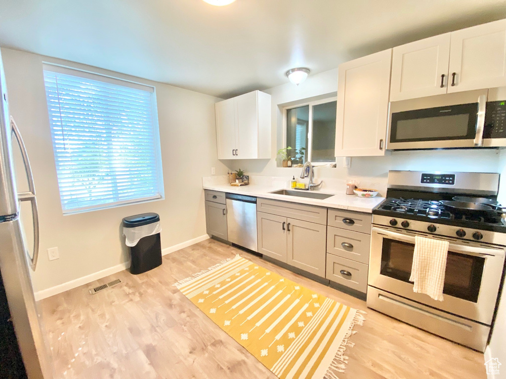 Kitchen with light wood-type flooring, visible vents, light countertops, a sink, and stainless steel appliances