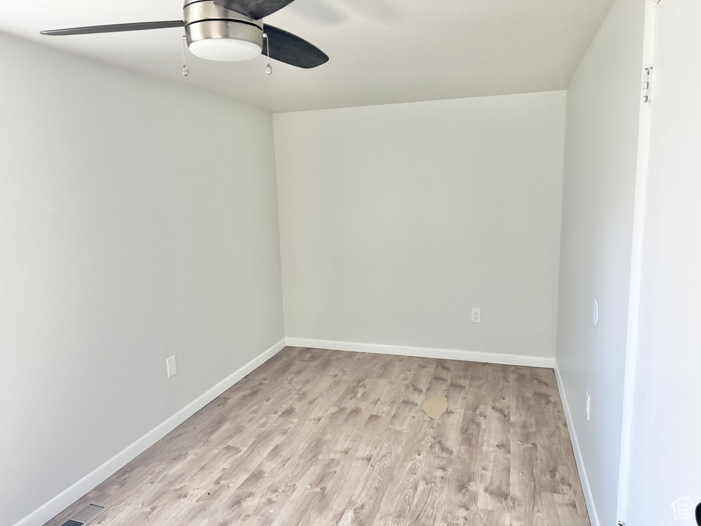 Empty room with light wood finished floors, baseboards, and a ceiling fan