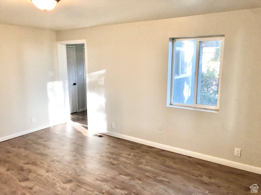 Unfurnished room with visible vents, baseboards, and wood finished floors