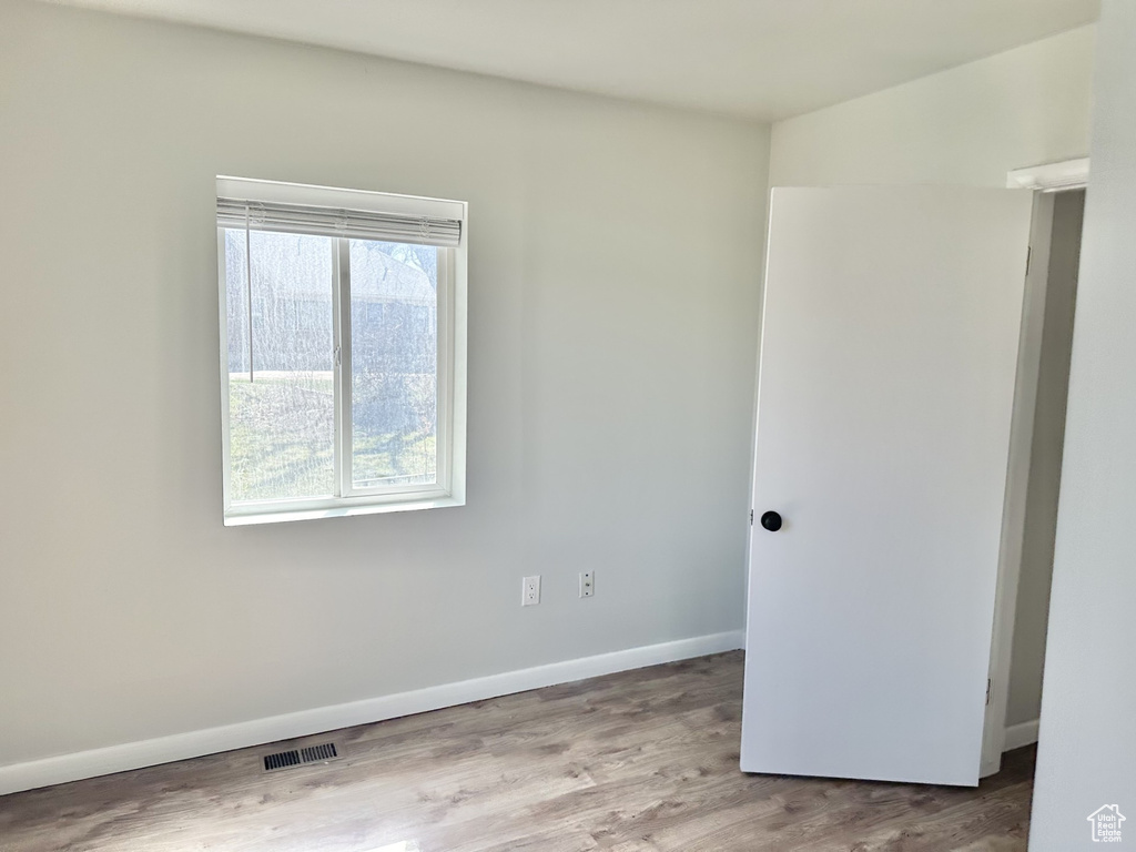 Empty room featuring visible vents, baseboards, and wood finished floors