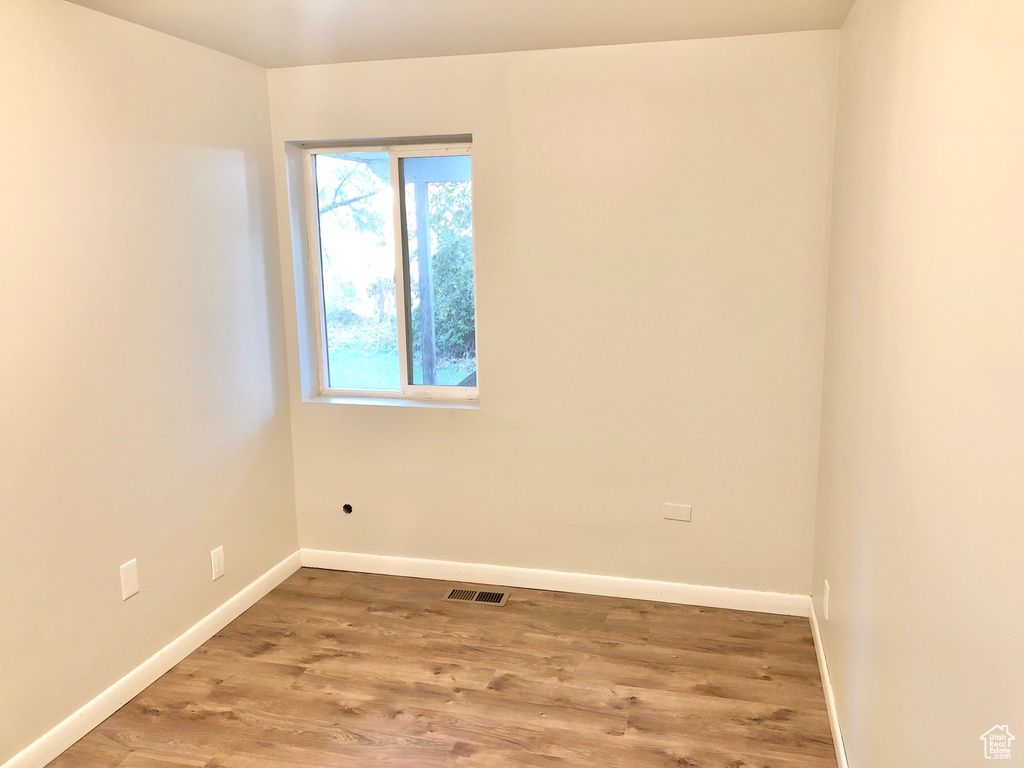 Spare room with visible vents, baseboards, and wood finished floors