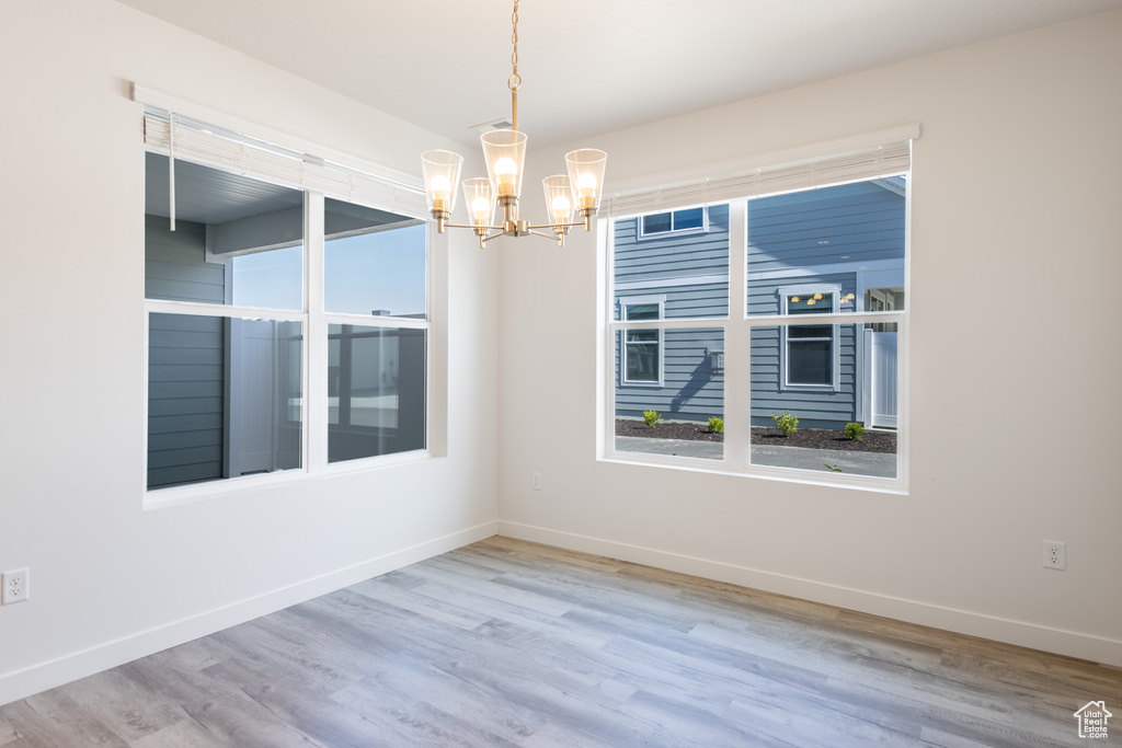 Spare room featuring a chandelier, baseboards, and wood finished floors