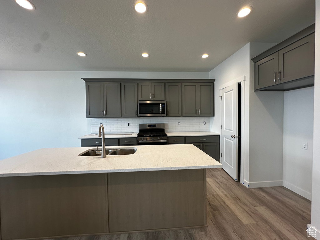 Kitchen featuring a sink, appliances with stainless steel finishes, backsplash, dark wood-style flooring, and recessed lighting