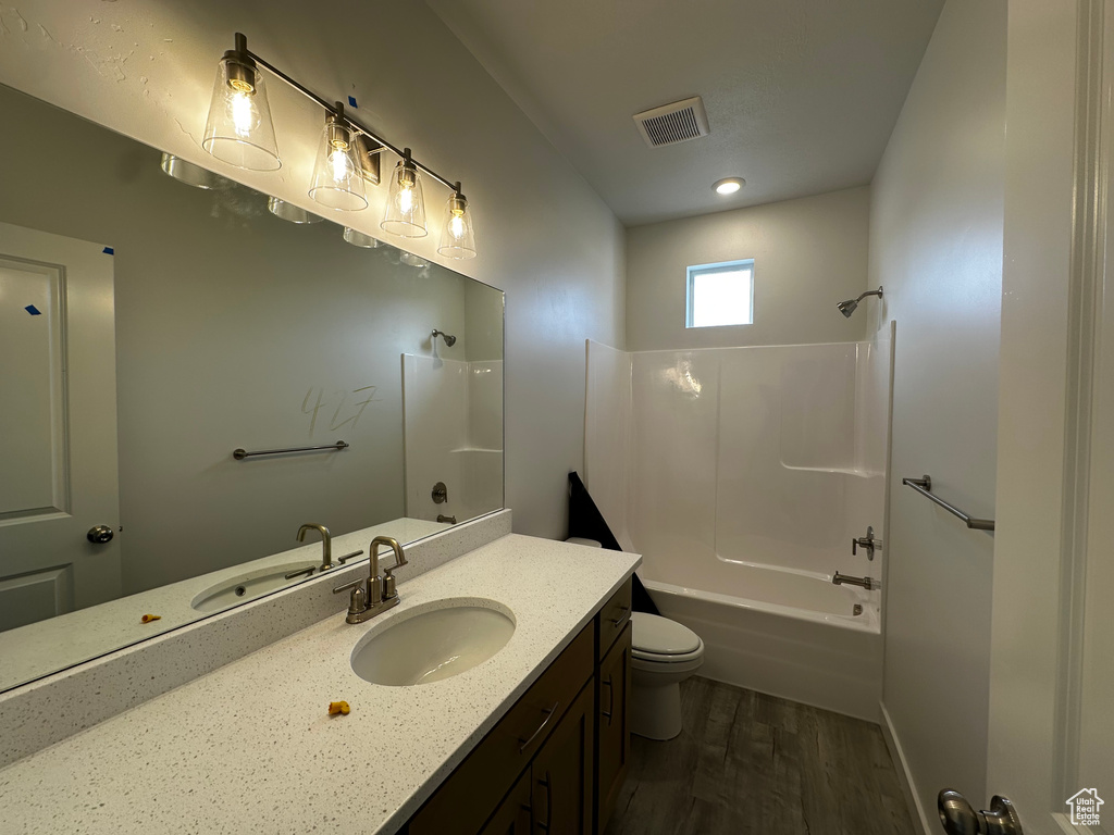Full bathroom featuring wood finished floors, toilet, shower / washtub combination, and vanity