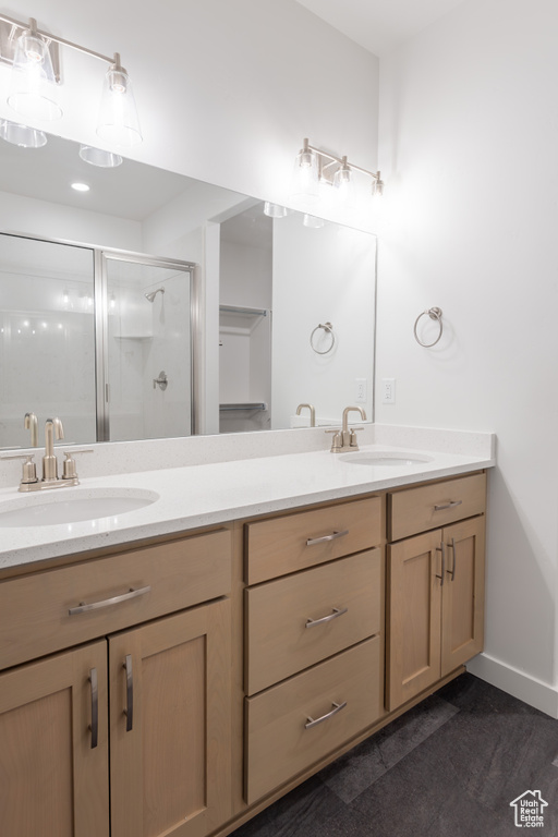 Full bath featuring double vanity, a stall shower, and baseboards