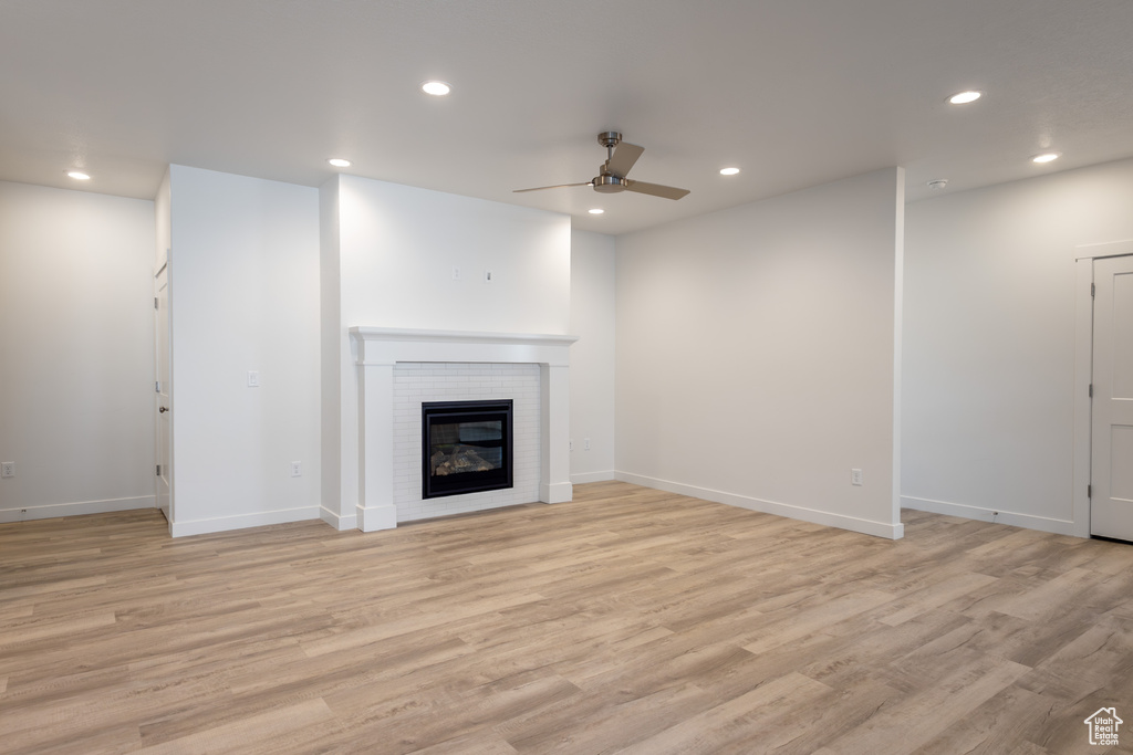 Unfurnished living room with ceiling fan, recessed lighting, light wood-style floors, a fireplace, and baseboards
