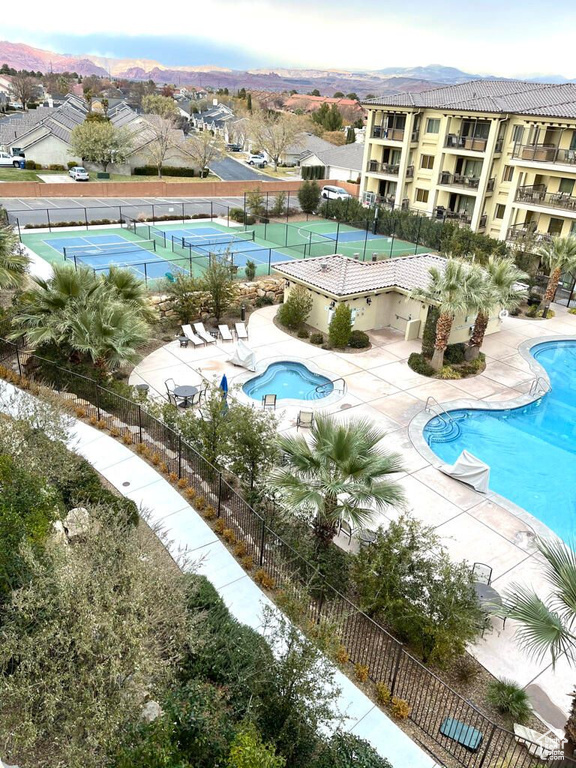 Community pool featuring a tennis court, fence, and a patio