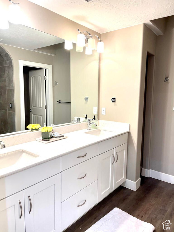 Full bathroom featuring double vanity, a sink, and wood finished floors