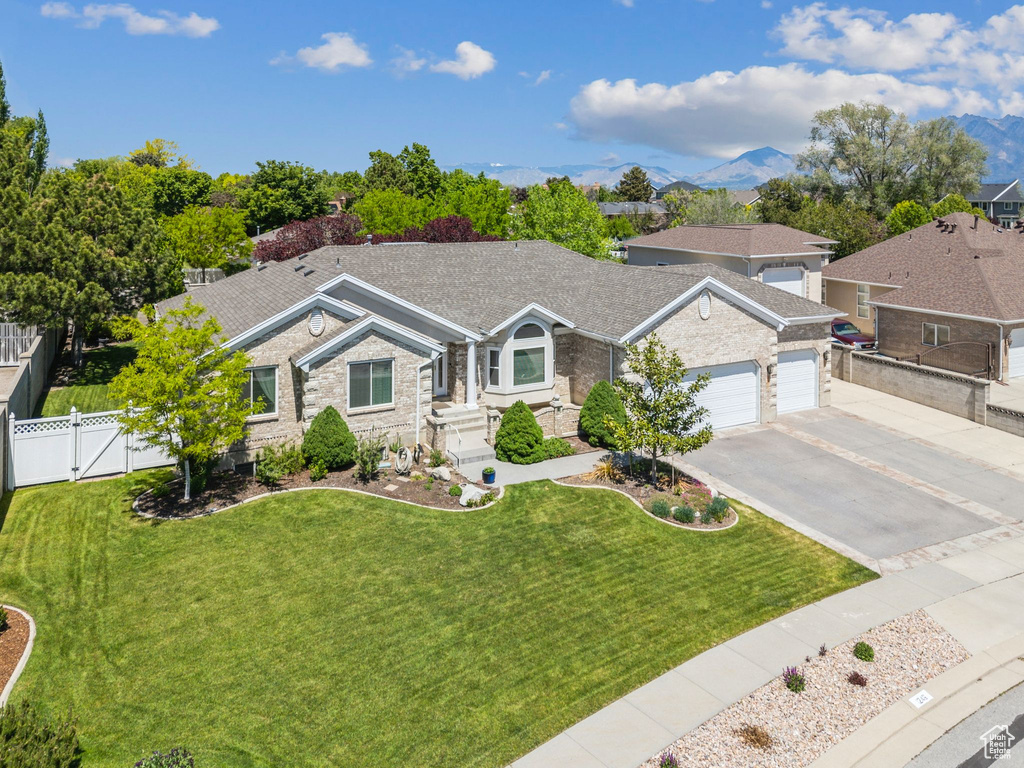 Single story home featuring a gate, a garage, driveway, stone siding, and a mountain view