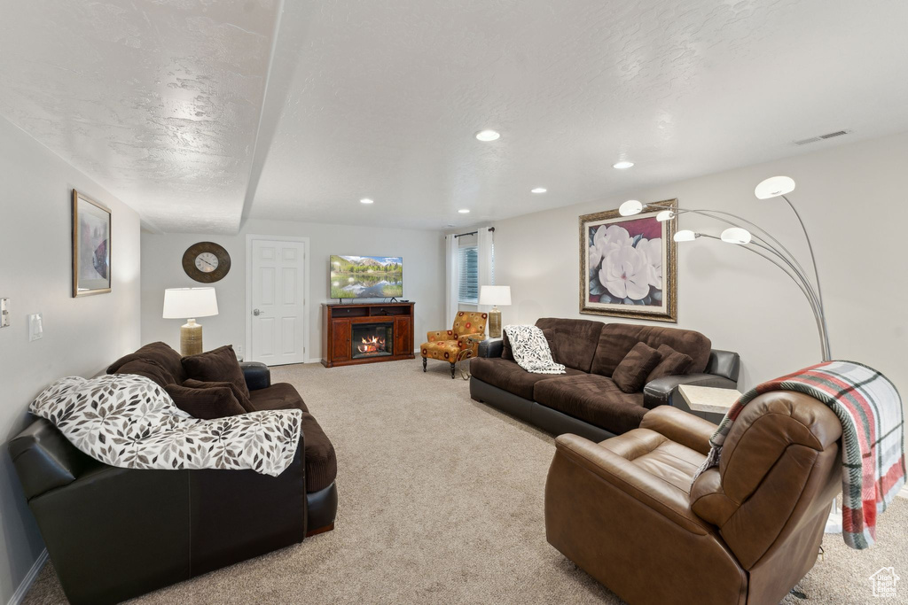 Living area with carpet, recessed lighting, and a lit fireplace