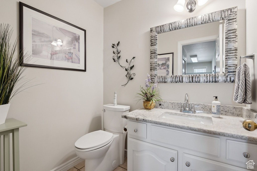 Half bathroom with toilet, vanity, and tile patterned floors