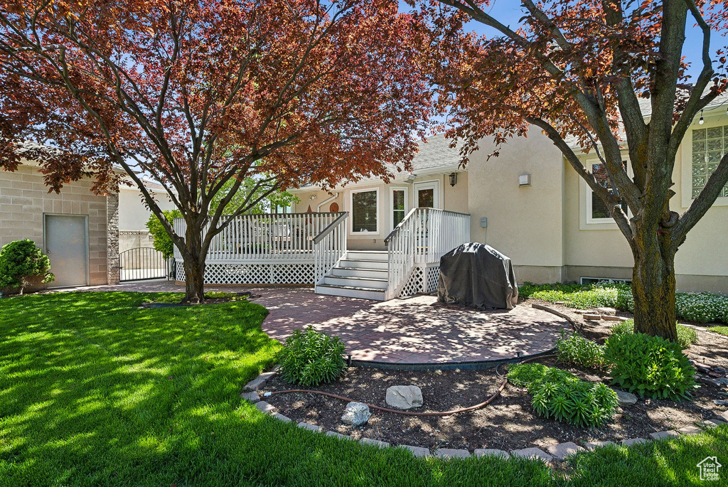 Back of property with a patio area, a lawn, stucco siding, and a deck