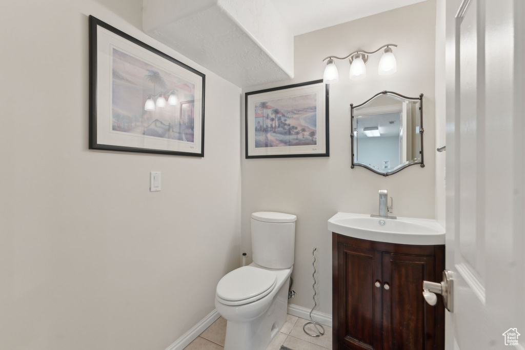 Half bathroom with tile patterned floors, toilet, vanity, and baseboards