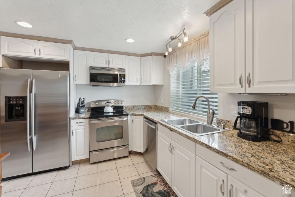 Kitchen with stainless steel appliances, a sink, white cabinetry, light tile patterned floors, and recessed lighting