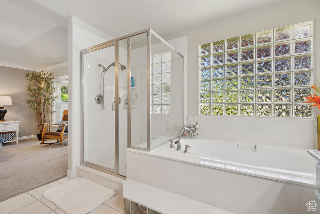 Bathroom with a stall shower, a bath, tile patterned floors, and baseboards