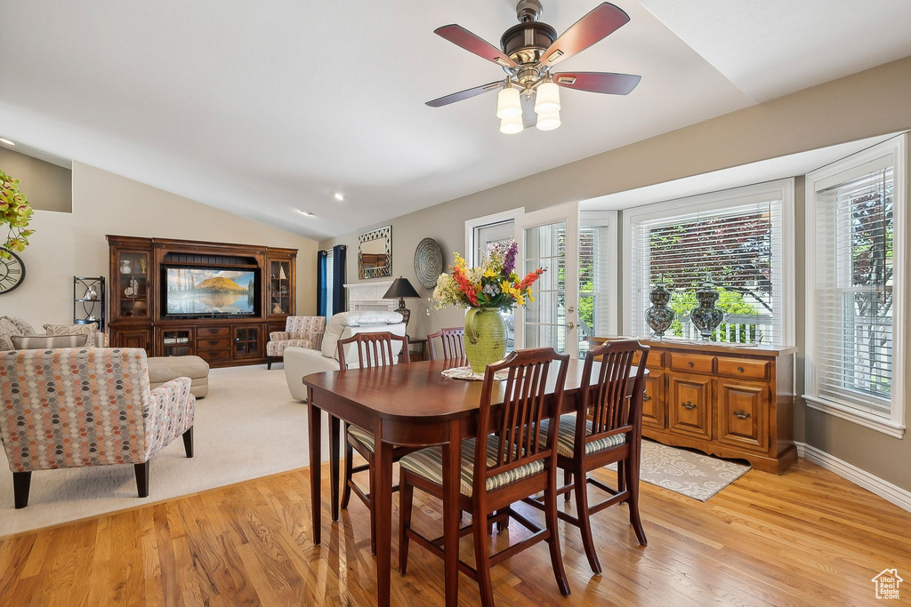 Dining room with vaulted ceiling, light wood-style flooring, a ceiling fan, and baseboards