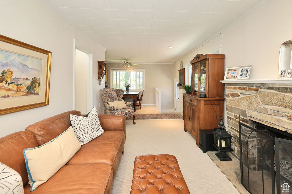 Carpeted living area with a fireplace, a ceiling fan, and ornamental molding