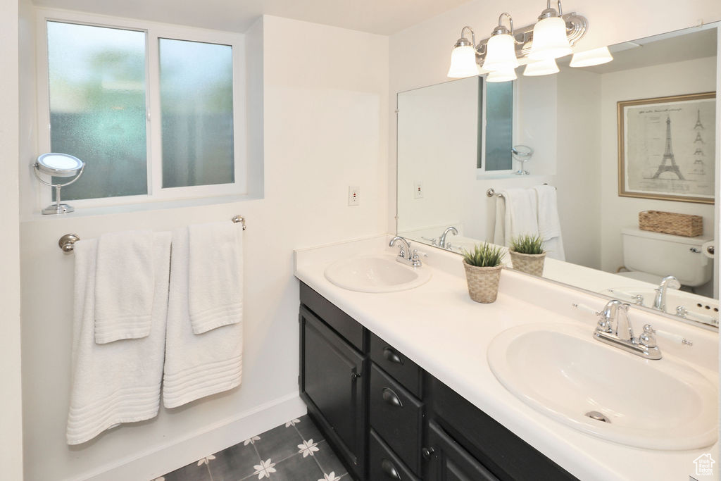 Bathroom featuring toilet, double vanity, a chandelier, and tile patterned floors