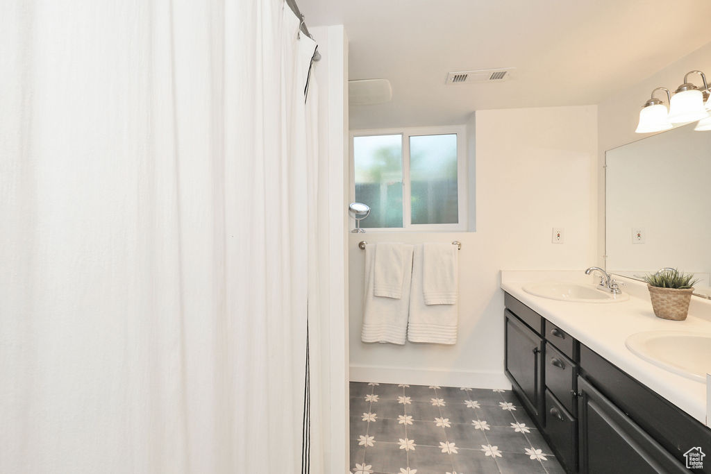 Bathroom featuring tile patterned floors, double vanity, and baseboards