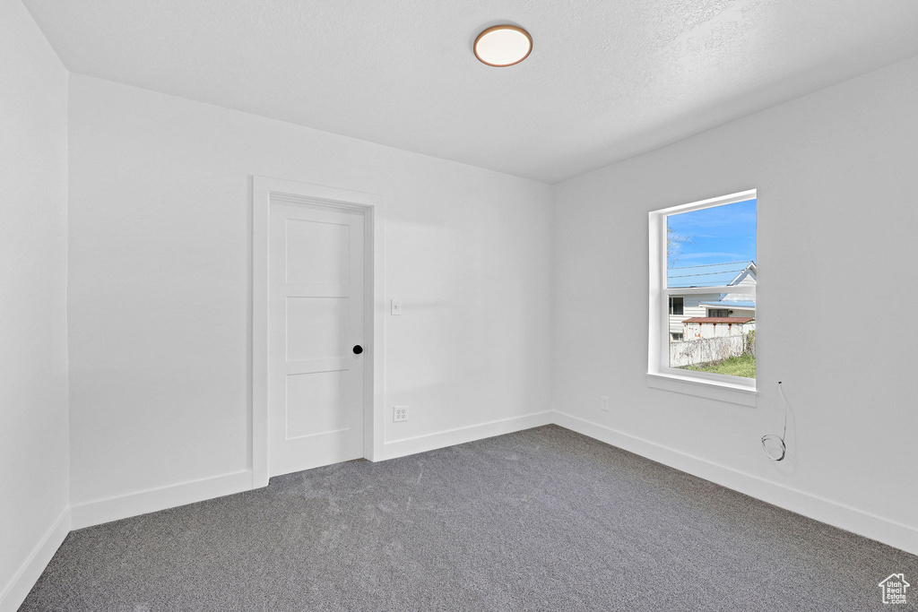 Unfurnished room with dark colored carpet and baseboards