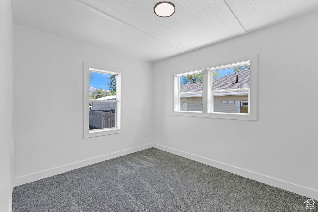 Empty room with plenty of natural light, baseboards, and dark carpet