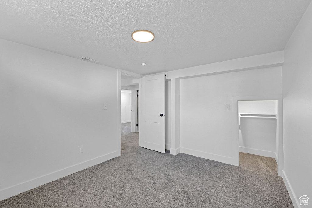 Below grade area featuring carpet floors, a textured ceiling, and baseboards