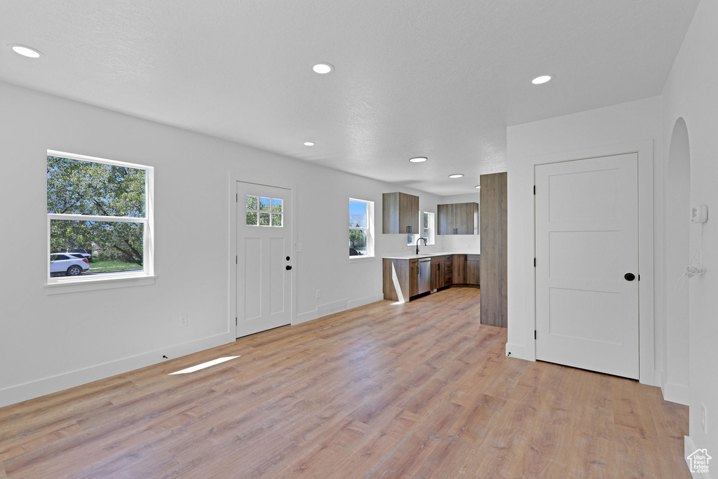 Entrance foyer with light wood-type flooring, arched walkways, recessed lighting, and baseboards