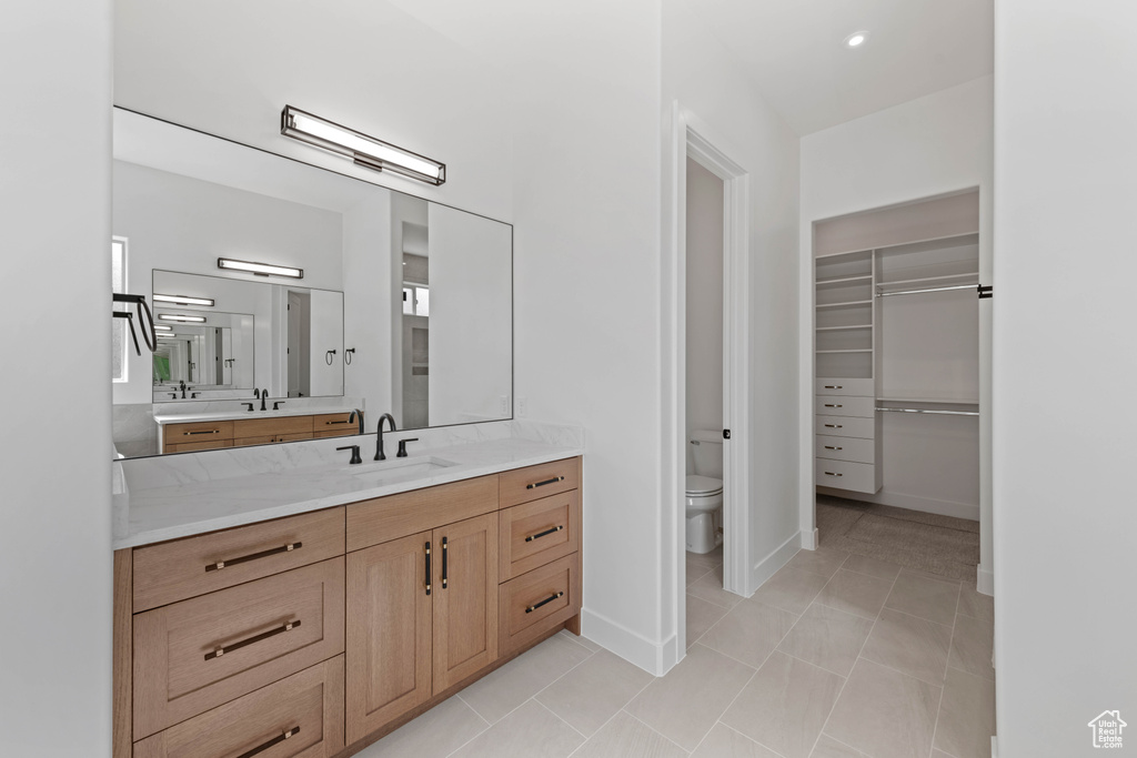 Bathroom featuring toilet, vanity, baseboards, and a walk in closet