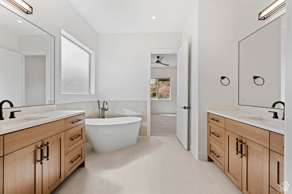 Full bath with a freestanding bath, two vanities, ceiling fan, and tile patterned floors