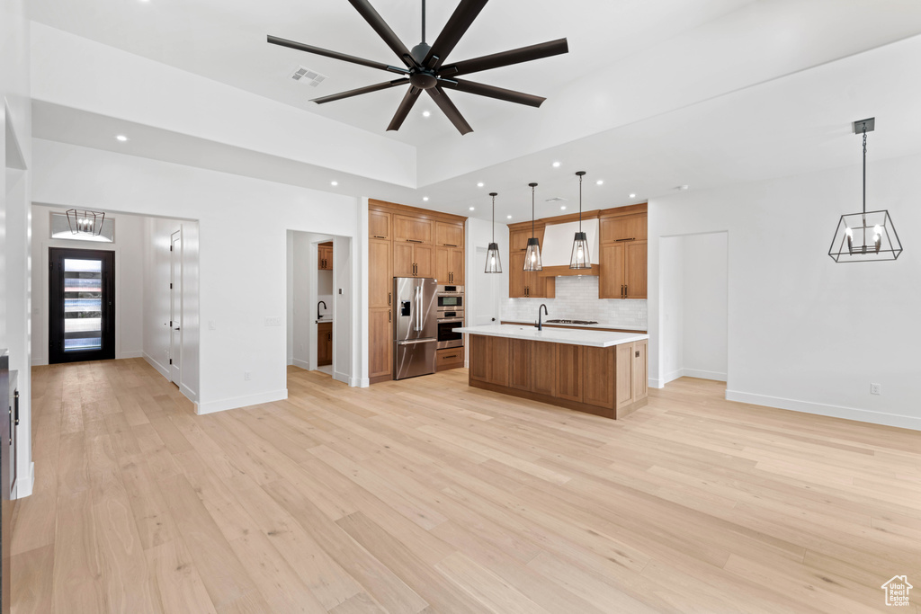 Kitchen with stainless steel fridge with ice dispenser, custom range hood, a chandelier, open floor plan, and light countertops