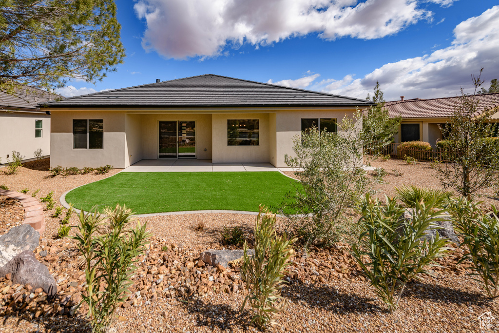 Rear view of property featuring stucco siding, a lawn, and a patio area