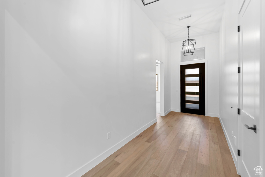 Foyer with light wood-style floors, baseboards, and a chandelier