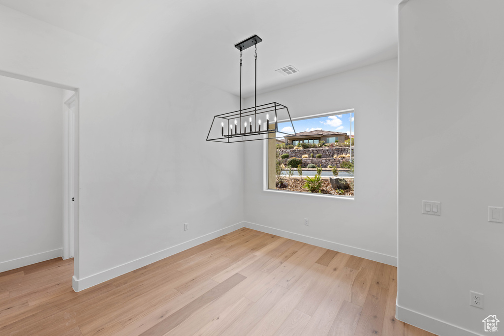 Unfurnished dining area with baseboards, light wood finished floors, and a chandelier