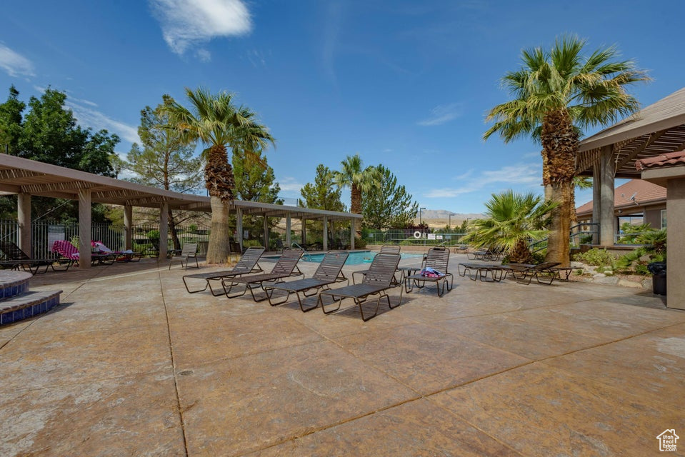 View of patio with a community pool and fence