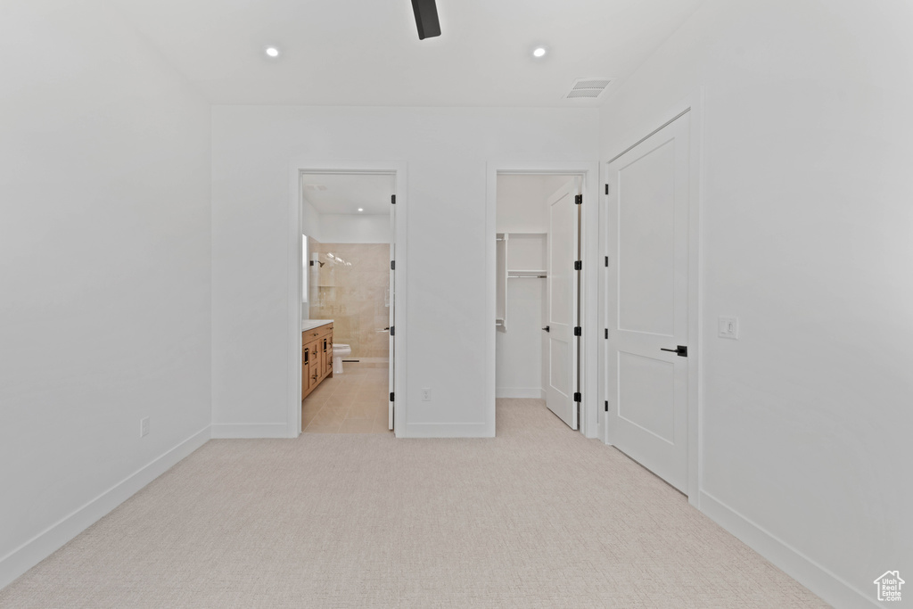 Unfurnished bedroom with a walk in closet, light carpet, recessed lighting, baseboards, and ensuite bath