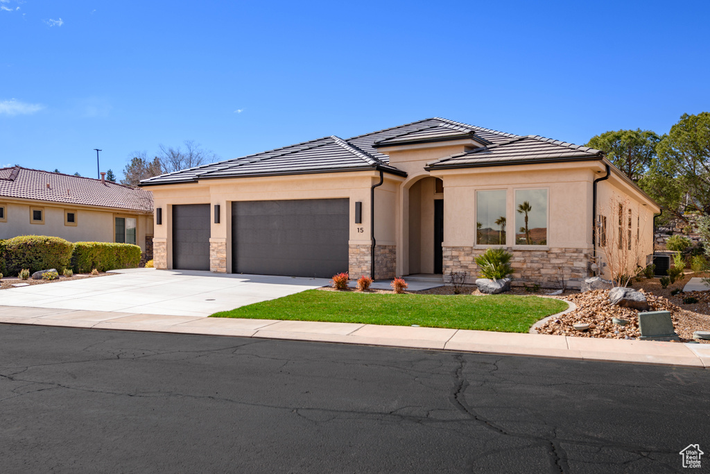 View of front of property featuring an attached garage, stone siding, concrete driveway, stucco siding, and a tiled roof