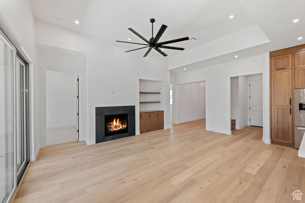 Unfurnished living room with recessed lighting, ceiling fan, light wood-type flooring, a fireplace, and built in shelves