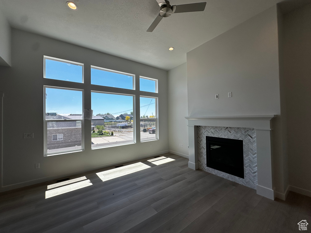 Unfurnished living room with a ceiling fan, baseboards, wood finished floors, a tile fireplace, and recessed lighting