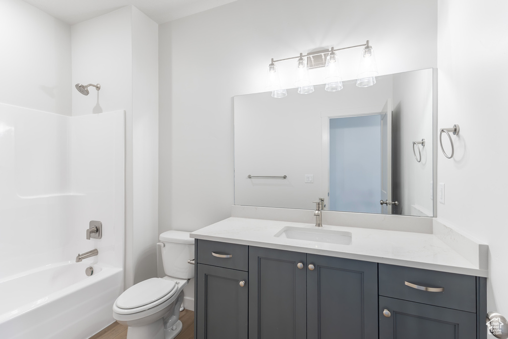 Bathroom with vanity, toilet, bathtub / shower combination, and wood finished floors