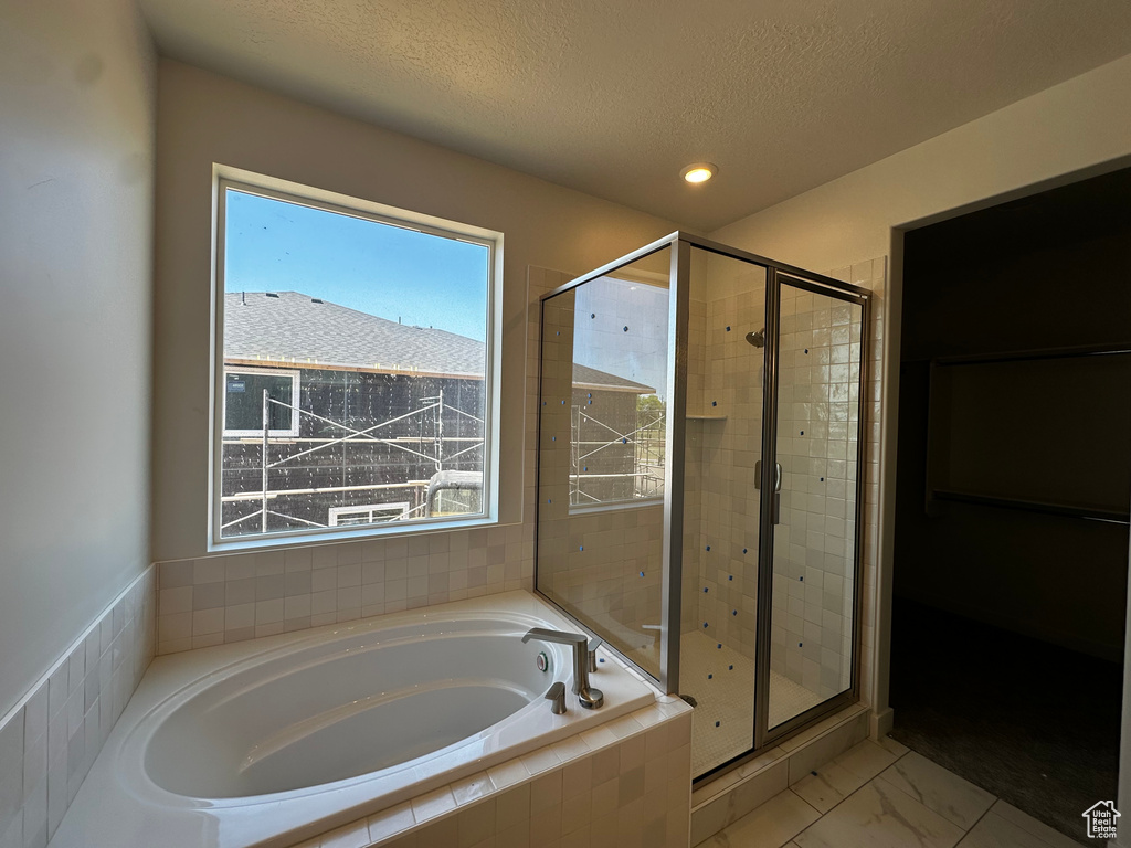 Full bath with a stall shower, a garden tub, a textured ceiling, marble finish floors, and recessed lighting