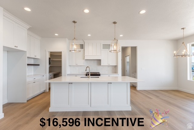 Kitchen featuring a sink, white cabinetry, light countertops, light wood-type flooring, and recessed lighting