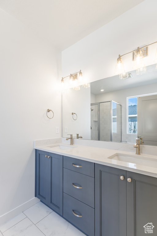 Bathroom featuring double vanity, a shower stall, baseboards, and marble look tiles