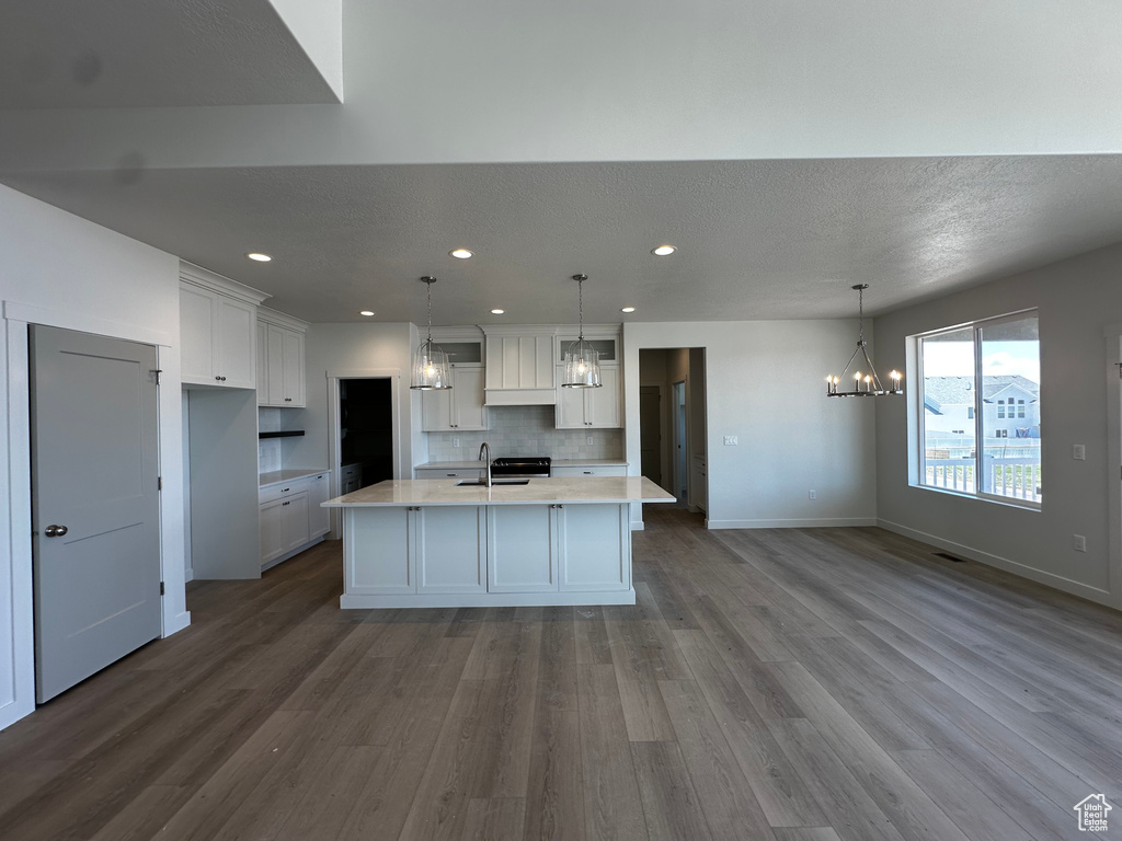 Kitchen with a chandelier, a sink, wood finished floors, light countertops, and white cabinets