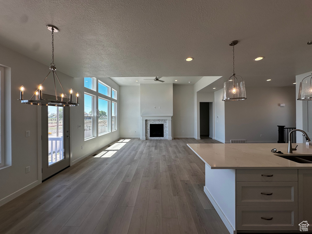 Kitchen featuring a sink, wood finished floors, a chandelier, hanging light fixtures, and a textured ceiling