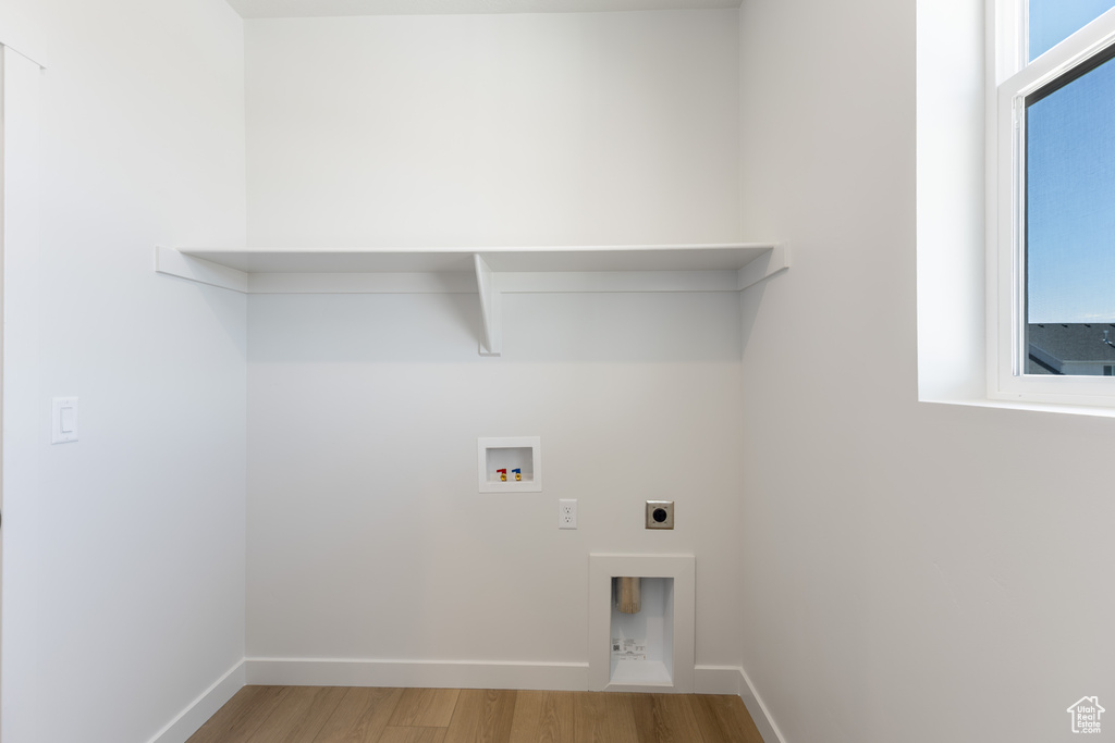 Washroom with wood finished floors, electric dryer hookup, hookup for a washing machine, and baseboards