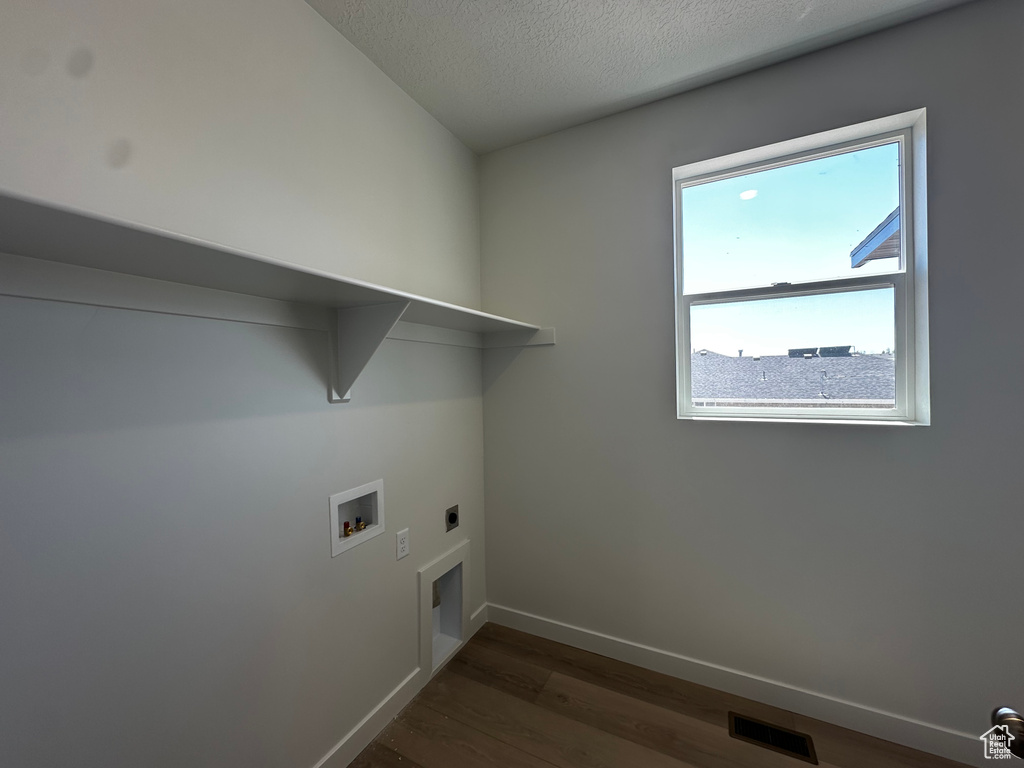 Washroom with electric dryer hookup, washer hookup, dark wood finished floors, baseboards, and a textured ceiling
