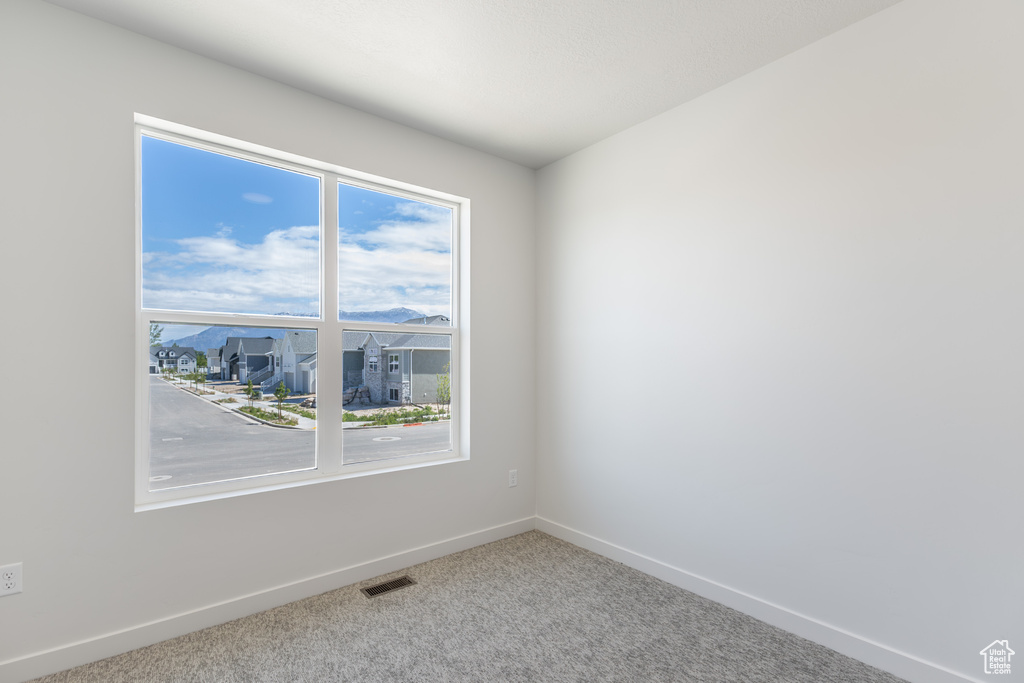 Spare room with baseboards, plenty of natural light, carpet flooring, and a residential view