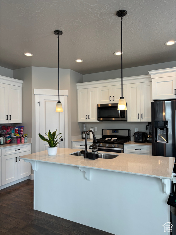 Kitchen with appliances with stainless steel finishes, a sink, a breakfast bar area, dark wood-style floors, and recessed lighting