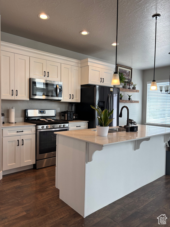 Kitchen featuring appliances with stainless steel finishes, dark wood-style flooring, white cabinetry, recessed lighting, and a textured ceiling