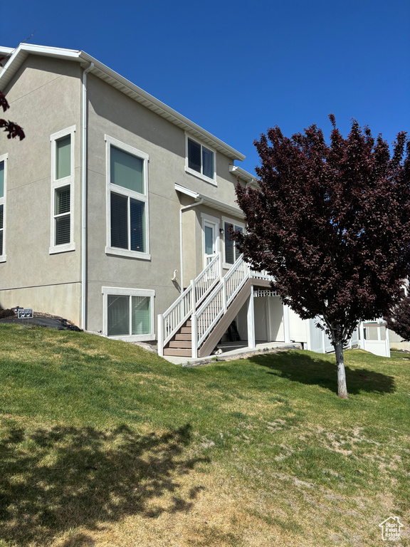 Rear view of house with stairway, stucco siding, and a yard